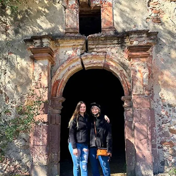 Guey Tours: Discover History on ATV Tours & San Miguel Buggy Tour Two women posing in an ancient stone archway during their Guey Tours ATV Tours and San Miguel Buggy Tour adventure.